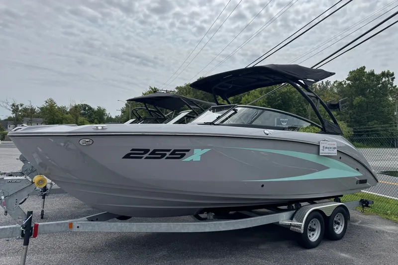 The Image of 2026 Yamaha Boats 255XD on trailer, sleek design, gray with teal accents, parked outdoors. - 0