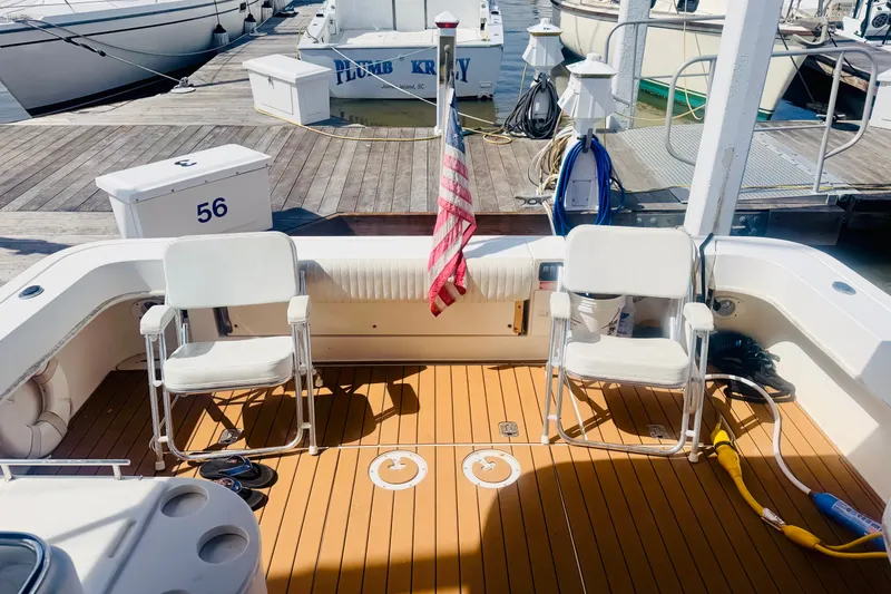 Slide: The Image of 1997 Sea Ray 330 Express Cruiser deck with chairs and American flag at marina. - 4
