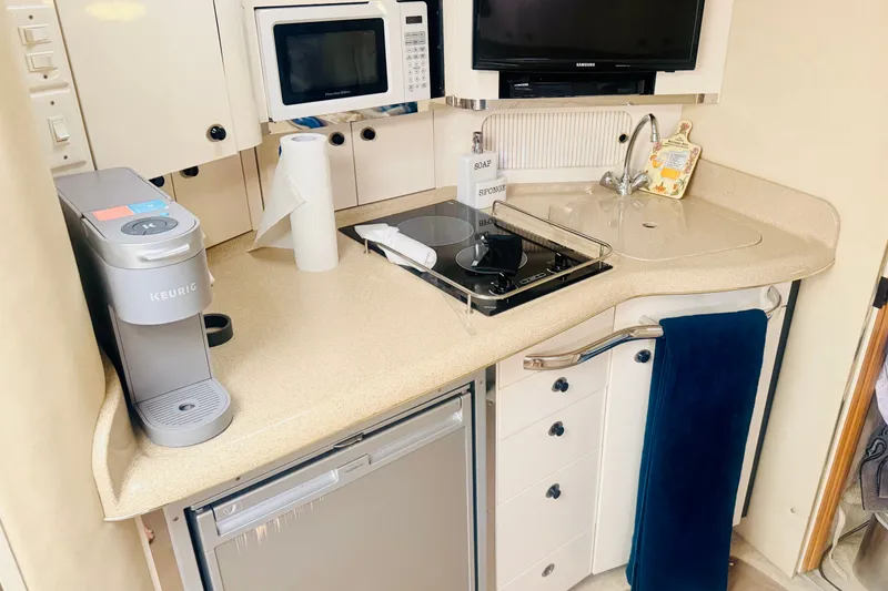 Slide: The Image of Compact kitchen area in a 1997 Sea Ray 330 Express Cruiser with appliances and storage. - 7