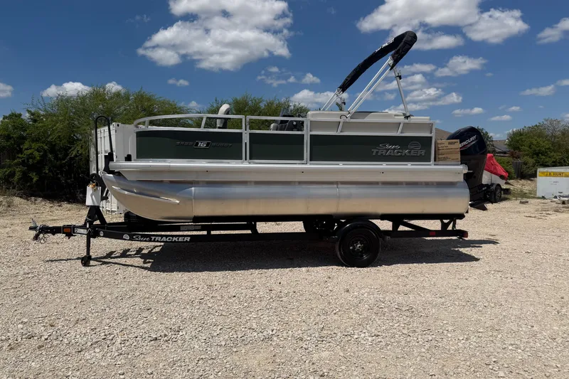 The Image of 2027 Sun Tracker Bass Buggy 16 XL Select pontoon boat on trailer, outdoors. - 0