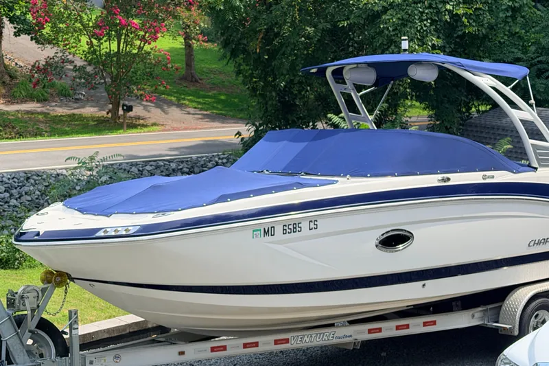 Slide: The Image of 2016 Chaparral 250 Suncoast boat on trailer, covered with blue tarp, parked outdoors. - 2