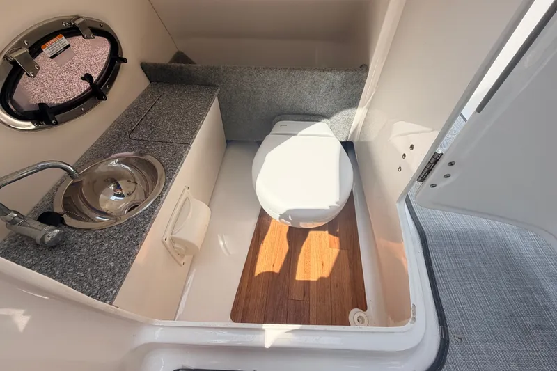 Slide: The Image of 2016 Chaparral 250 Suncoast boat bathroom with sink and toilet, featuring wood flooring. - 42