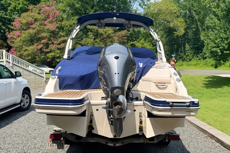 Slide: The Image of 2016 Chaparral 250 Suncoast boat with covered deck and outboard motor, parked on gravel. - 4