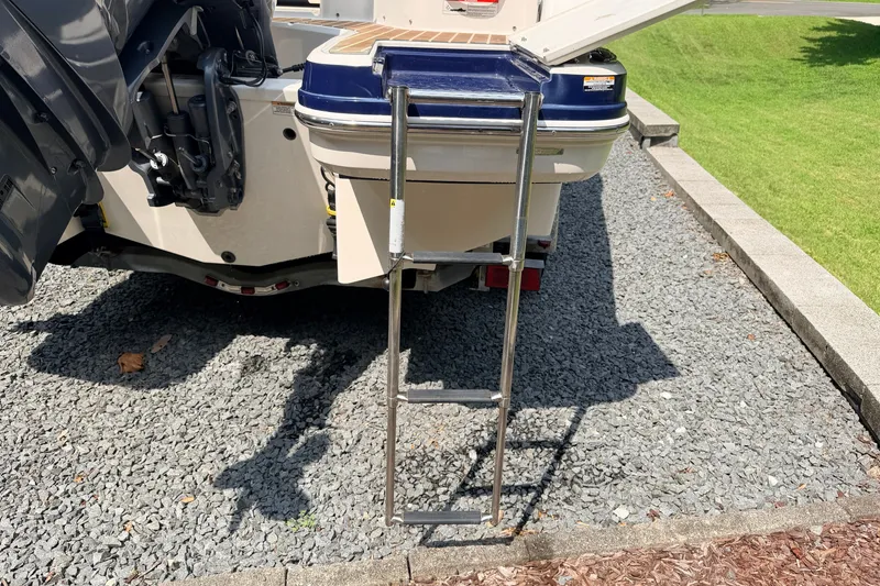 Slide: The Image of 2016 Chaparral 250 Suncoast boat with extended swim ladder on gravel surface. - 12