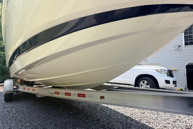 Slide: The Image of 2016 Chaparral 250 Suncoast boat on trailer, parked on gravel near a white vehicle. - 9