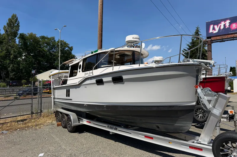 The Image of 2025 Ranger Tugs R-27 boat on trailer, parked outdoors under clear sky. - 0