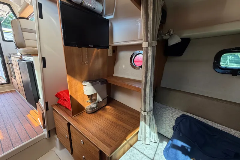 Slide: The Image of 2025 Ranger Tugs R-27 interior with TV, coffee maker, and cozy seating area. - 15