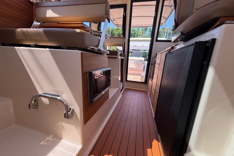 Slide: The Image of Interior of 2025 Ranger Tugs R-27 boat, featuring sleek wood flooring and modern seating. - 13