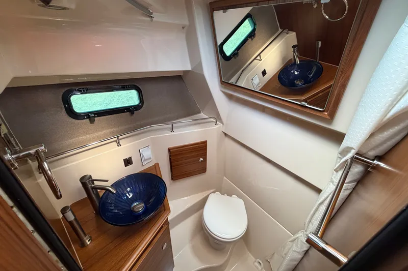 Slide: The Image of 2025 Ranger Tugs R-27 bathroom with modern sink, mirror, and compact toilet. - 16