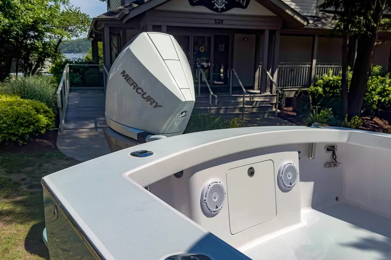 Slide: The Image of Weaver 25 boat with Mercury engine docked near a lakeside house, 2025 model. - 3