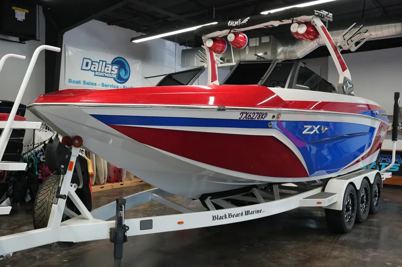 Slide: The Image of 2021 Tigé 25ZX boat in showroom, red and blue design, on trailer. - 9