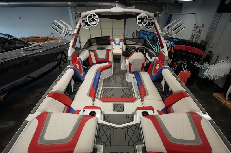 Slide: The Image of 2021 Tigé 25ZX boat interior with red, blue, and white seating in showroom. - 13