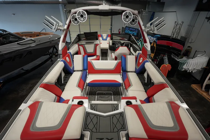 Slide: The Image of 2021 Tigé 25ZX boat interior with red, white, and blue seating in showroom. - 14