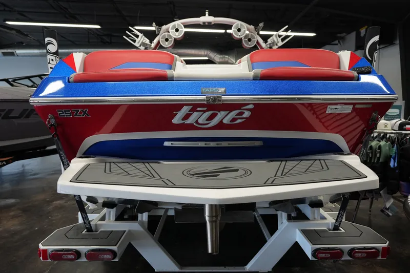 Slide: The Image of 2021 Tigé 25ZX boat, red and blue, rear view in showroom setting. - 4