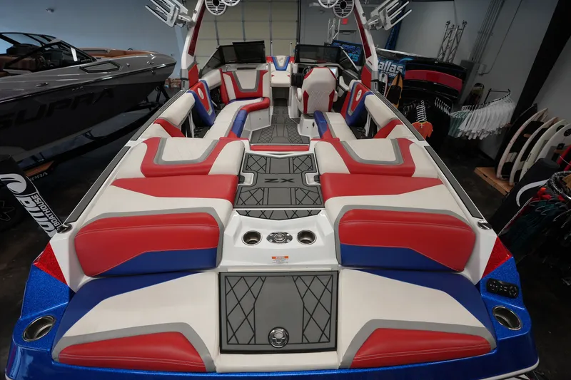 Slide: The Image of 2021 Tigé 25ZX boat interior with red, white, and blue seating in showroom. - 11