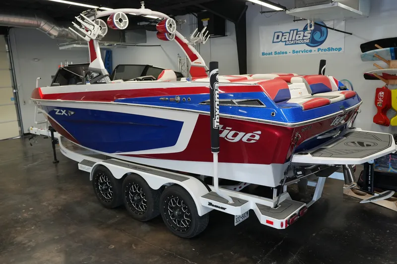 Slide: The Image of 2021 Tigé 25ZX boat in showroom, red and blue design, on a trailer. - 3