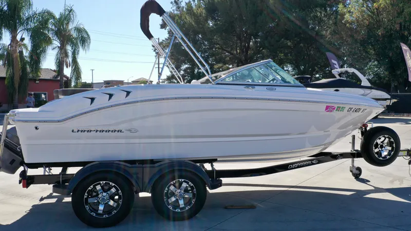 Slide: The Image of A white 2020 Chaparral 19 SSi boat on a trailer, surrounded by palm trees. - 7