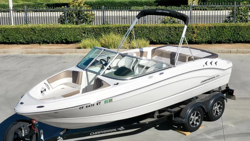 Slide: The Image of 2020 Chaparral 19 SSi on a trailer, featuring a Bimini top and sleek white body. - 2