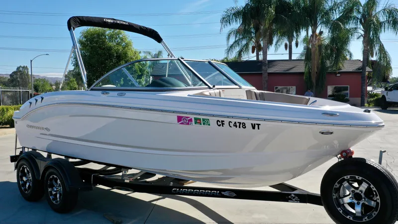 Slide: The Image of A white 2020 Chaparral 19 SSi boat on a trailer, surrounded by palm trees. - 6