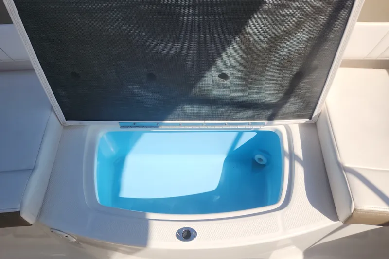 Slide: The Image of Open storage compartment on 2020 Chaparral 19 SSi boat, featuring a blue interior. - 19