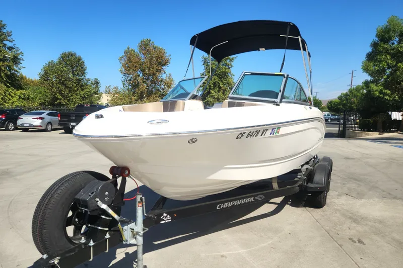 Slide: The Image of 2020 Chaparral 19 SSi boat on trailer, parked outdoors under clear blue sky. - 13