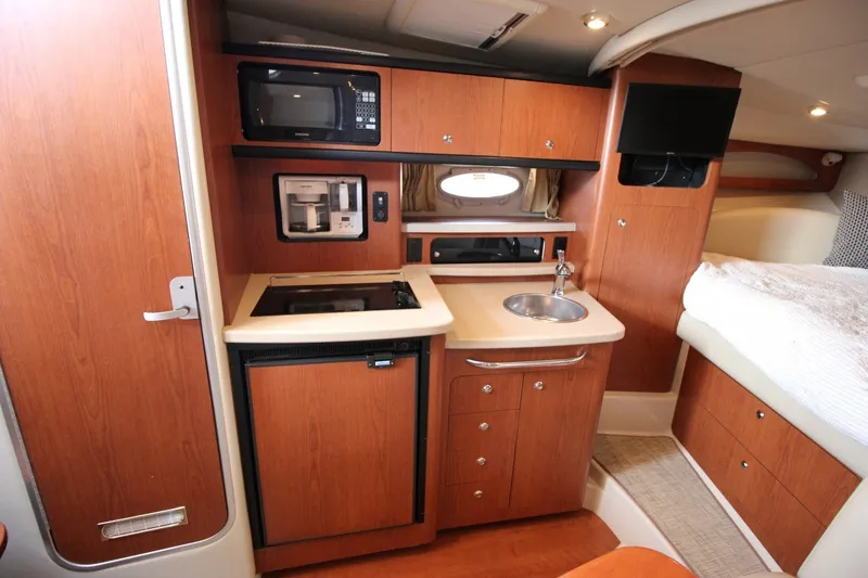 Slide: The Image of 2004 Chaparral Signature 310 boat interior with kitchenette, sink, and cozy sleeping area. - 18
