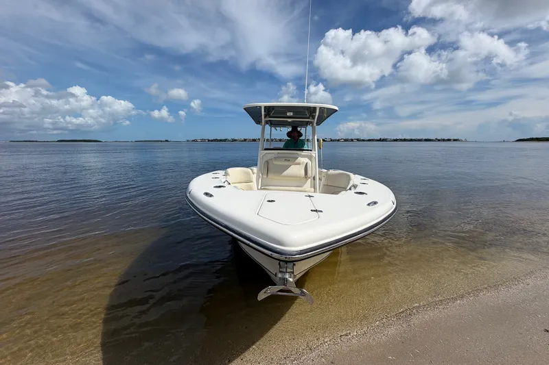 Slide: The Image of 2022 Key West 263 FS boat on sandy shore under blue sky. - 2