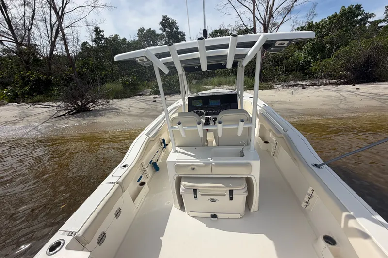 Slide: The Image of 2022 Key West 263 FS boat docked on a sandy shore with lush greenery. - 8