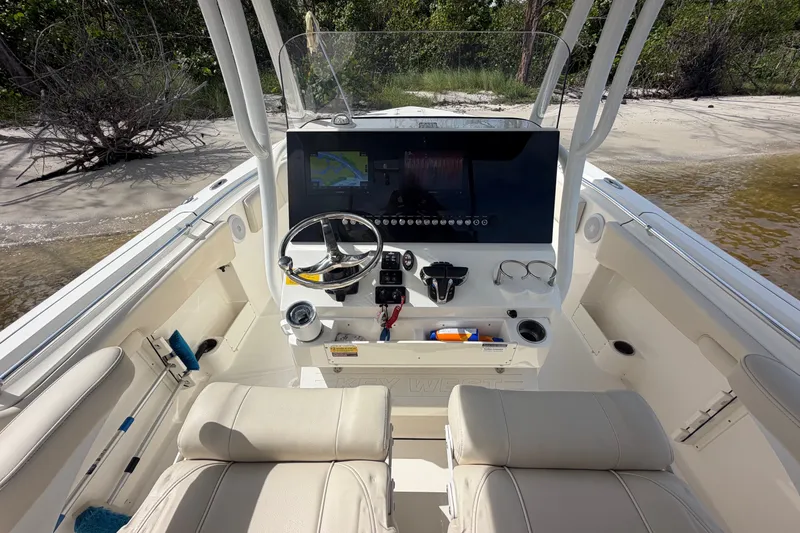 Slide: The Image of 2022 Key West 263 FS boat interior with steering console and seating, docked on sandy shore. - 11
