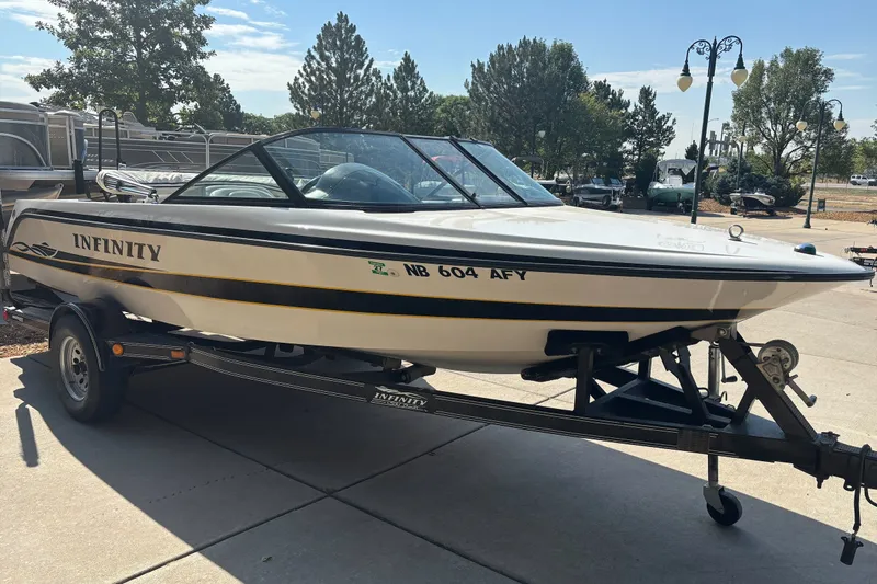 Slide: The Image of 2001 Infinity ZX-1 boat on trailer, parked outdoors under clear sky. - 2