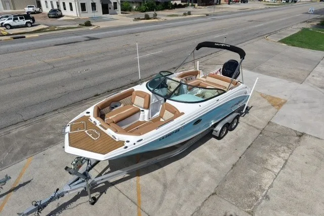 Slide: The Image of 2025 NauticStar 243 DC Deck boat on trailer, parked in urban area. - 7