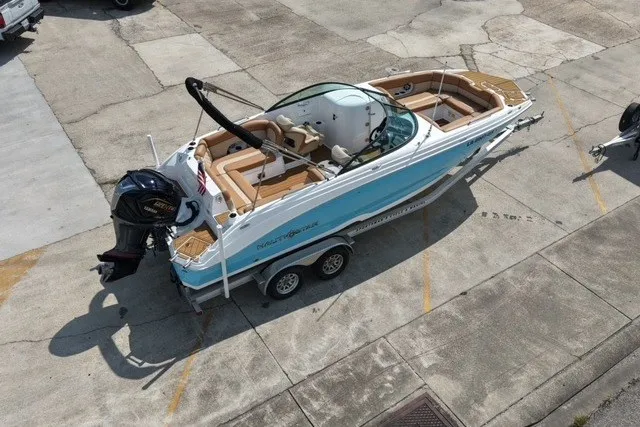 Slide: The Image of 2025 NauticStar 243 DC Deck boat on trailer, featuring sleek design and powerful outboard motor. - 4