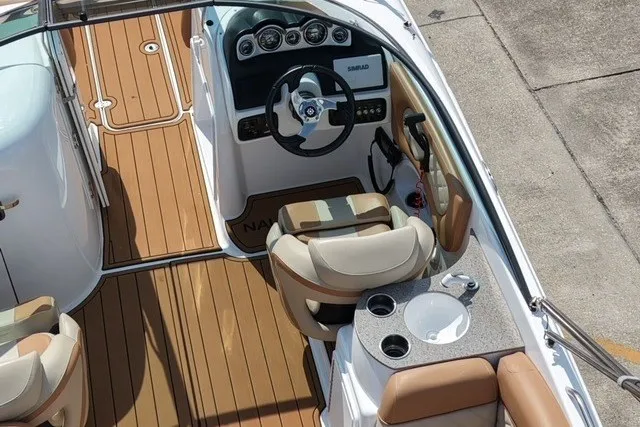 Slide: The Image of 2025 NauticStar 243 DC Deck boat interior with helm, seating, and wood-style flooring. - 8
