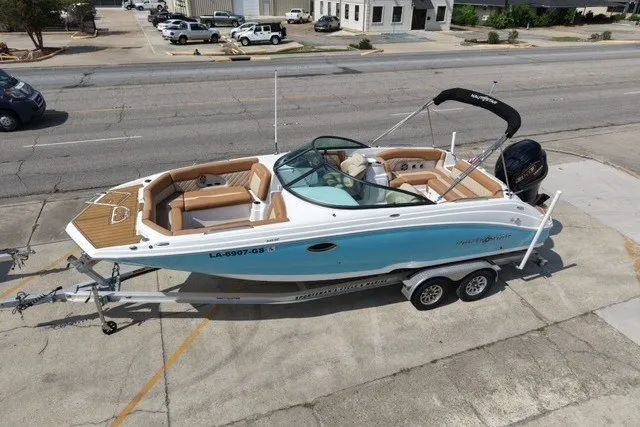 The Image of 2025 NauticStar 243 DC Deck boat on trailer, parked in urban setting. - 0