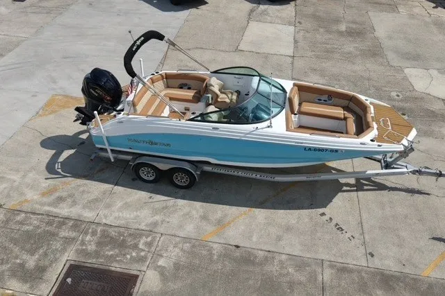 Slide: The Image of 2025 NauticStar 243 DC Deck boat on trailer, parked on concrete surface. - 3