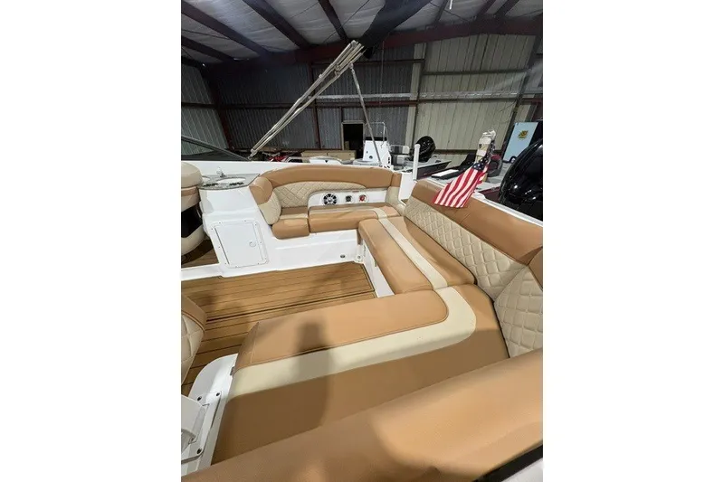 Slide: The Image of Luxurious interior of 2025 NauticStar 243 DC Deck boat with tan seating and American flag. - 9