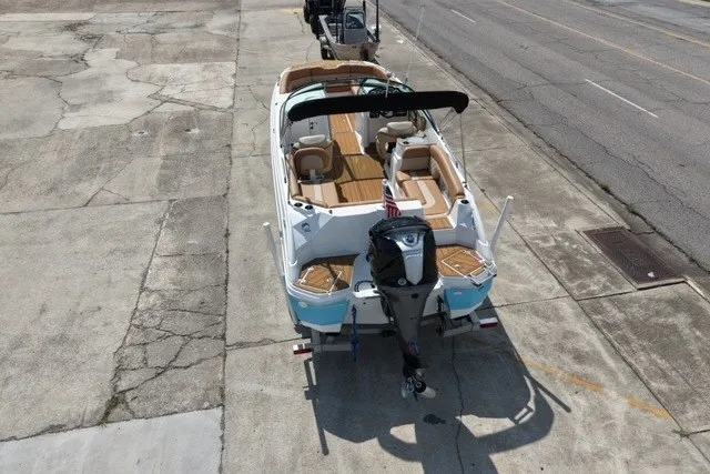 Slide: The Image of 2025 NauticStar 243 DC Deck boat on trailer, viewed from above, parked on concrete surface. - 5