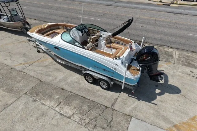 Slide: The Image of 2025 NauticStar 243 DC Deck boat on trailer, featuring sleek design and powerful outboard motor. - 6