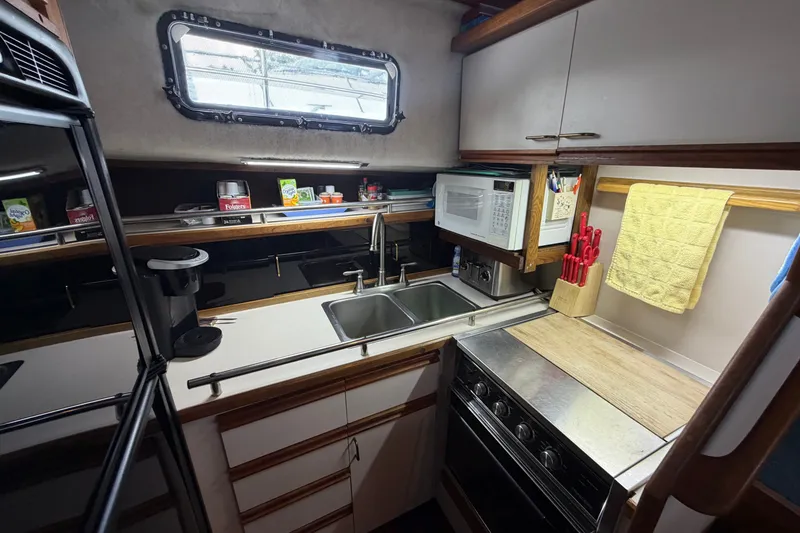 Slide: The Image of 1989 Carver 3607 Aft Cabin Motor Yacht kitchen with sink, stove, and microwave. - 25