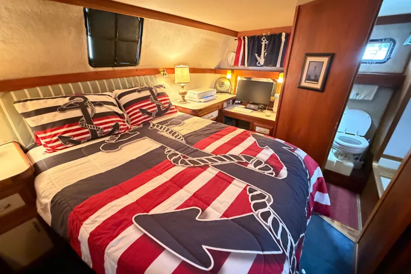 Slide: The Image of 1989 Carver 3607 Aft Cabin Motor Yacht bedroom with nautical-themed bedding and ensuite bathroom. - 37