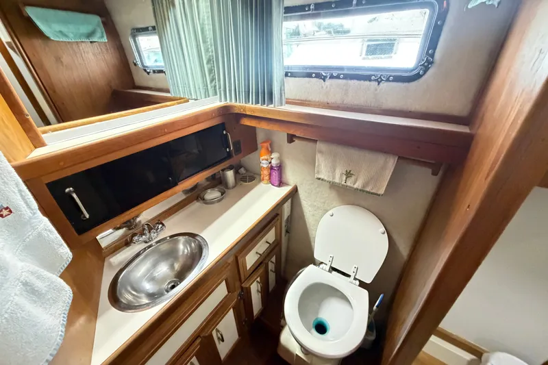 Slide: The Image of 1989 Carver 3607 Aft Cabin Motor Yacht bathroom with sink, toilet, and storage cabinets. - 40