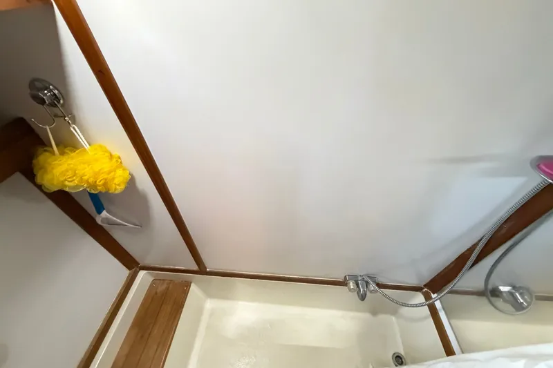 Slide: The Image of 1989 Carver 3607 Aft Cabin Motor Yacht shower area with handheld showerhead and cleaning tools. - 42
