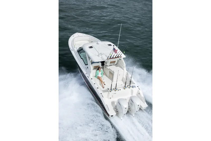 Slide: The Image of 2026 Pursuit DC 326 Dual Console boat cruising on open water, featuring dual engines and fishing rods. - 4