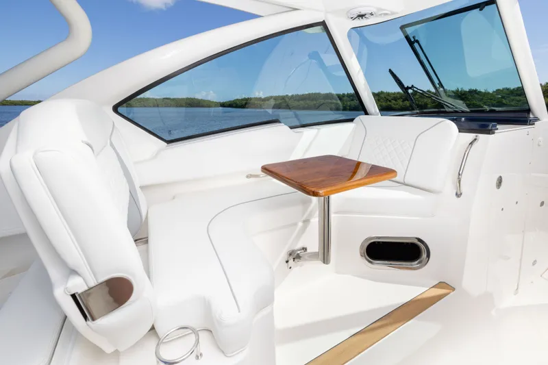 Slide: The Image of 2026 Pursuit DC 326 Dual Console interior with white seating and wooden table. - 13