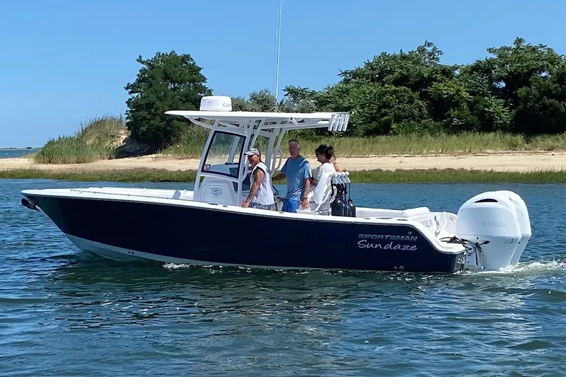 The Image of 2021 Sportsman Heritage 251 Center Console boat cruising on a sunny day near a shoreline. - 3