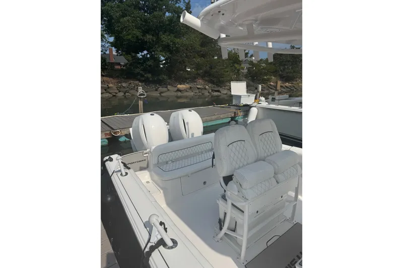 Slide: The Image of 2021 Sportsman Heritage 251 Center Console boat with dual engines docked by the shore. - 12