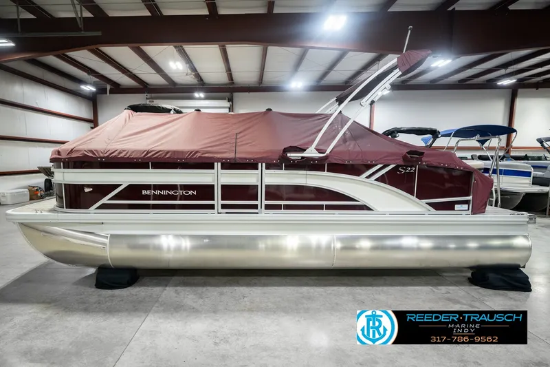 Slide: The Image of 2027 Bennington 22 SLJ pontoon boat with maroon cover in indoor showroom. - 60