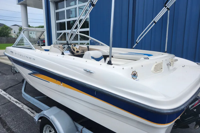 Slide: The Image of 2008 Bayliner 185 boat with blue and yellow accents, parked near a blue building. - 9