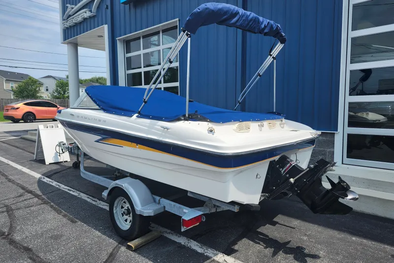 Slide: The Image of 2008 Bayliner 185 boat with blue cover on trailer outside dealership. - 1