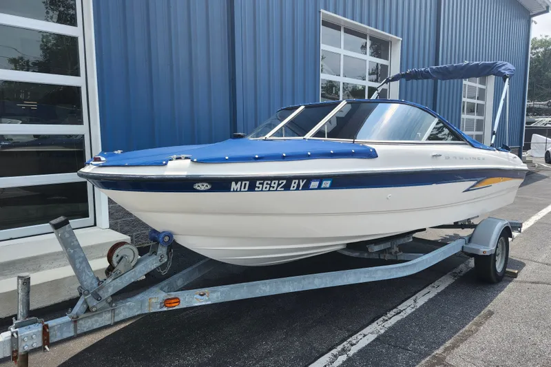 Slide: The Image of 2008 Bayliner 185 boat on trailer, parked outside blue building. - 2
